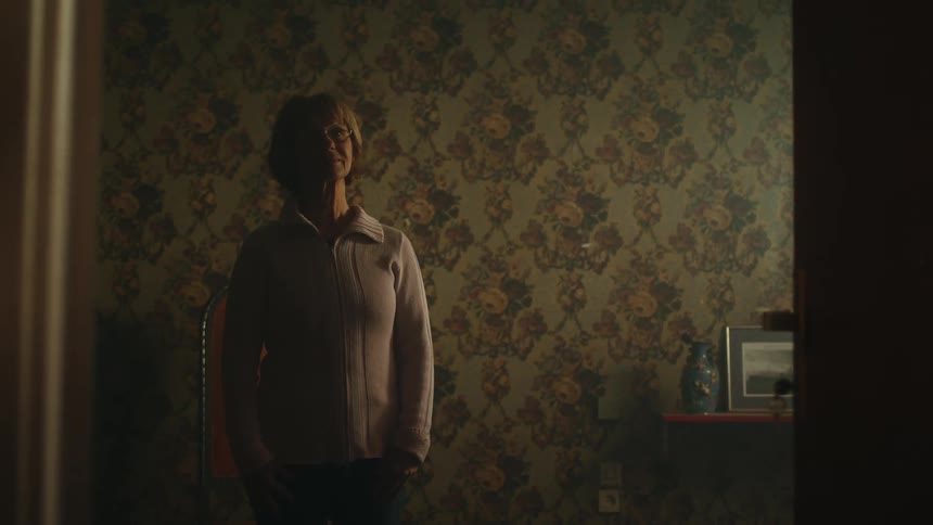 A woman stands in the doorway to her bedroom