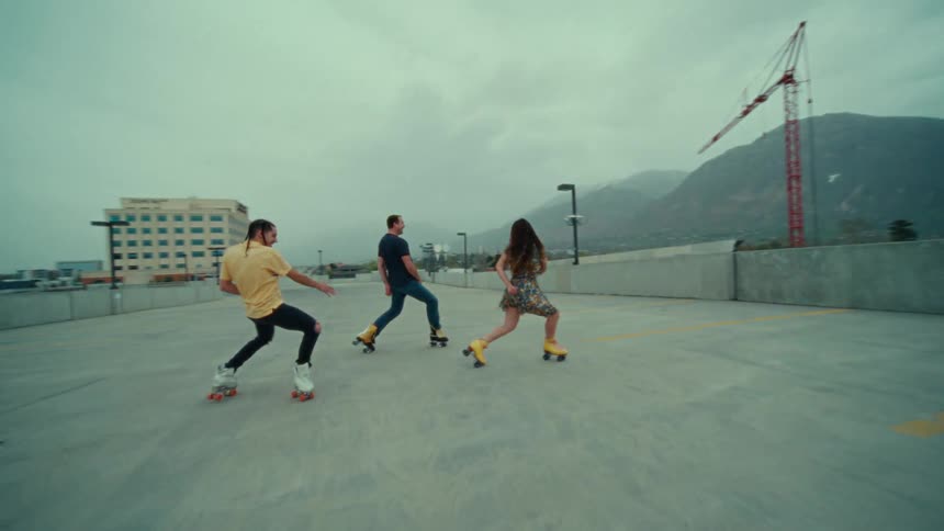 A group is skating and doing turns on a large empty boardwalk in a city