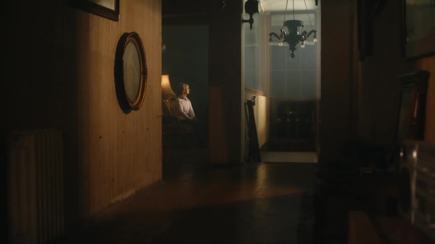 A woman sits in a dimly lit room in her house