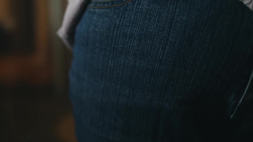 A woman sliders her cell phone in to the front pocket of her jeans