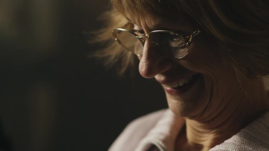 Happy old woman looking at something and smiling with joy