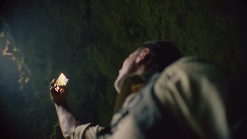 A man in a cavern raises his smartphone to take a photograph of his surroundings