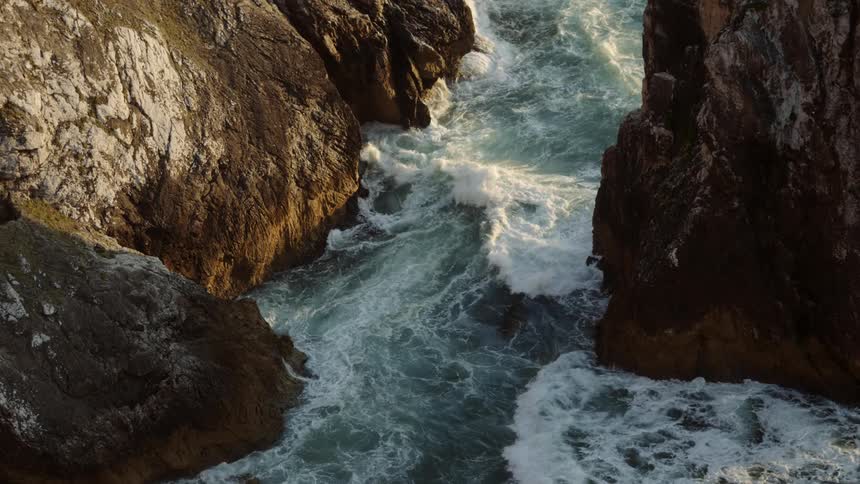 Aerial view of water flowing between cliffs is displayed