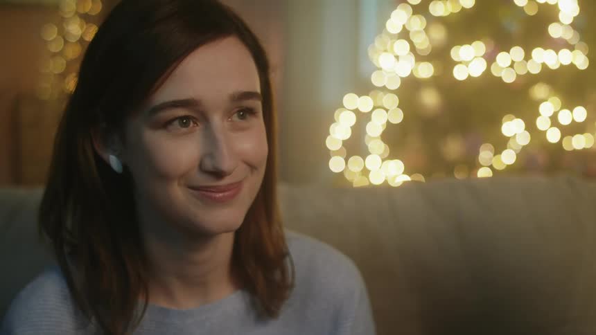 A young woman sits inside and smiles as she looks up