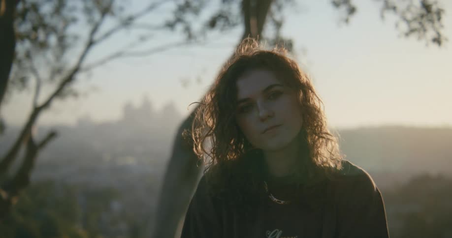 A teenage girl under a tree looks in to the distance