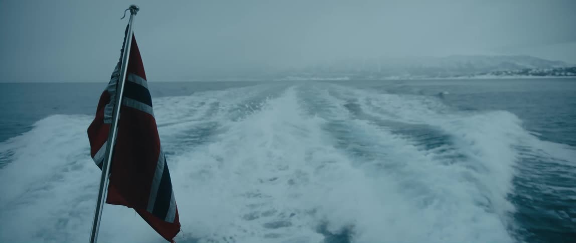 Waves behind a boat in the ocean with the Norwegian flag