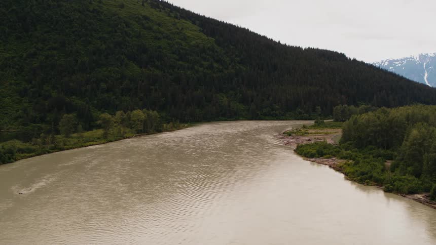 A river flowing around a curve with tree covered slopes and banks and a mountain on the horizon