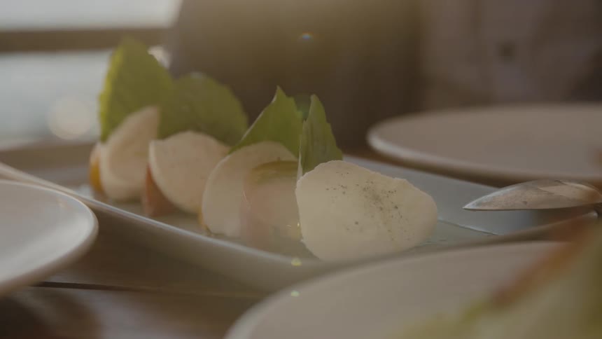 A caprese salad sits on a plate on a restaurant table