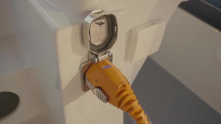 A persons hand is seen plugging and electrical cord into an outlet