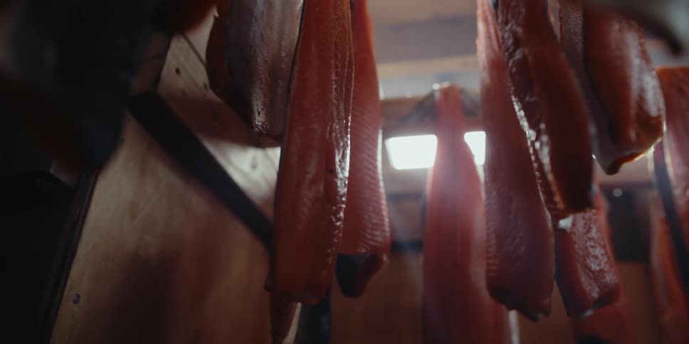 Salmon fillets hanging in a wooden smoke house