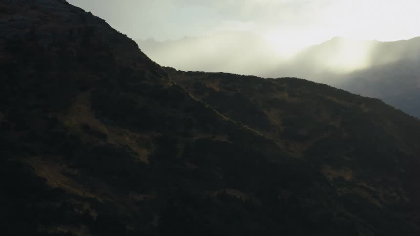A mountain slope covered in vegetation under a cloudy sky