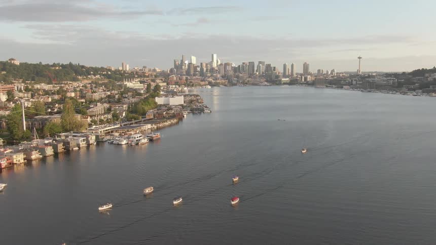 An aerial view of boats sailing in the water with a city skyline in the distance