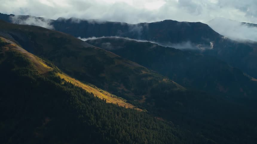 The verdant slope of a mountain under a cloudy daytime sky