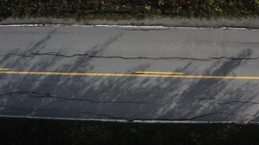 The sun shines on a cracked and debilitating road