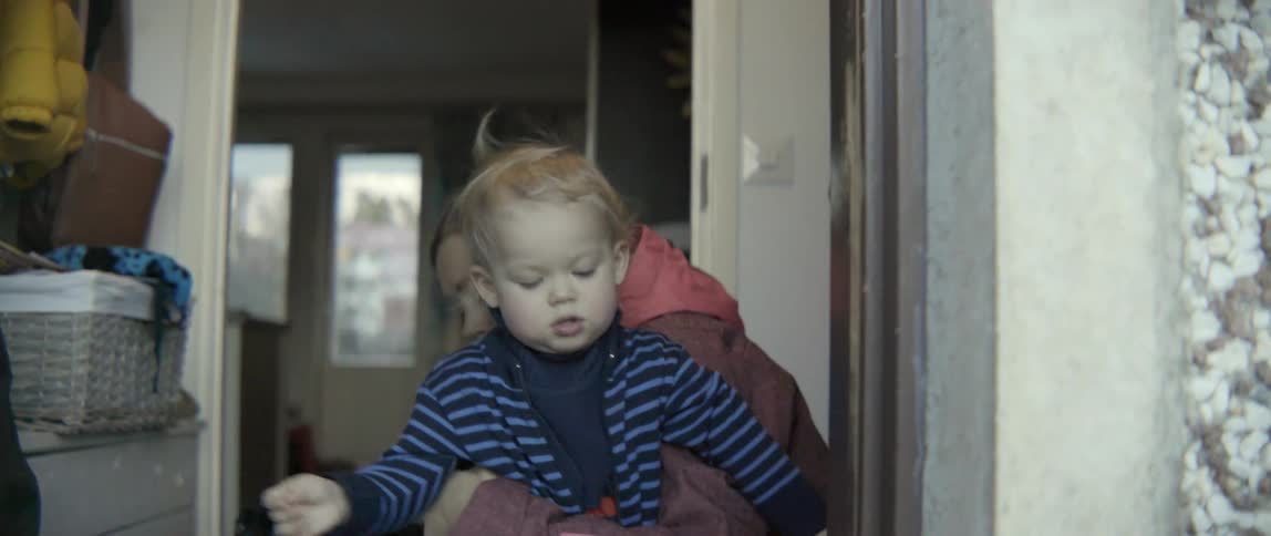 Heartwarming scene of a family pet watching a mother help her son with winter clothes.