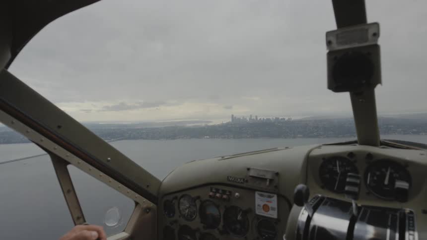 Pilot flies airplane over water on misty day