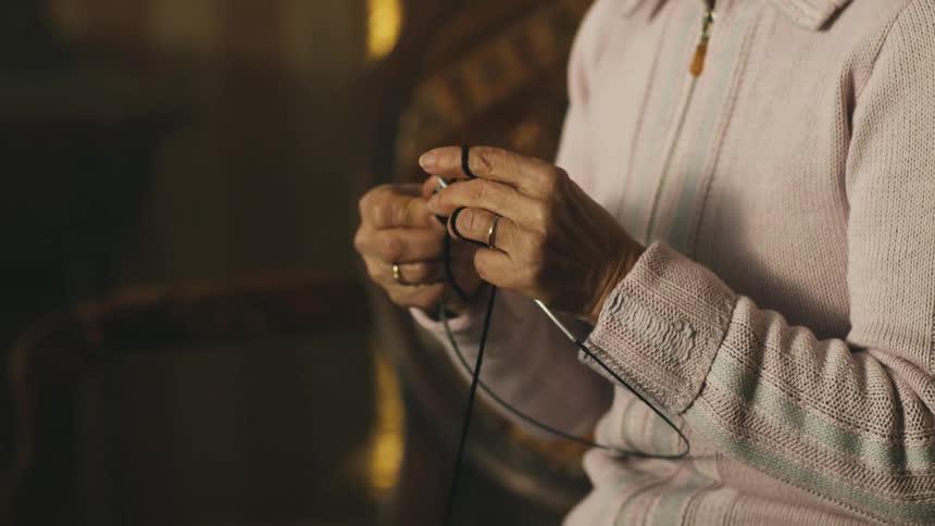 A woman knits while sitting indoors
