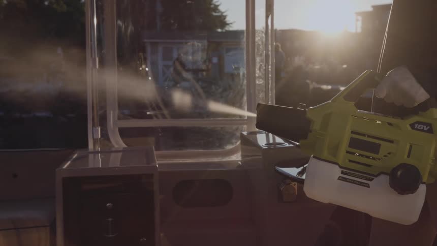 A man uses an 18 volt sprayer to clean his boat while others fish from the dock