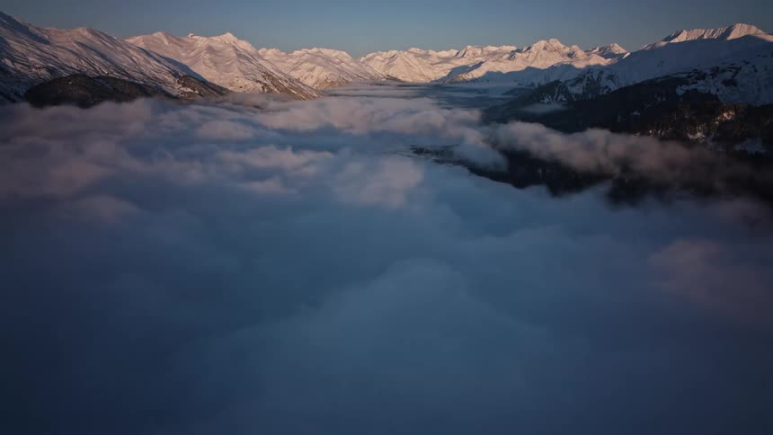 A sea of clouds obscure a mountain valley during the day