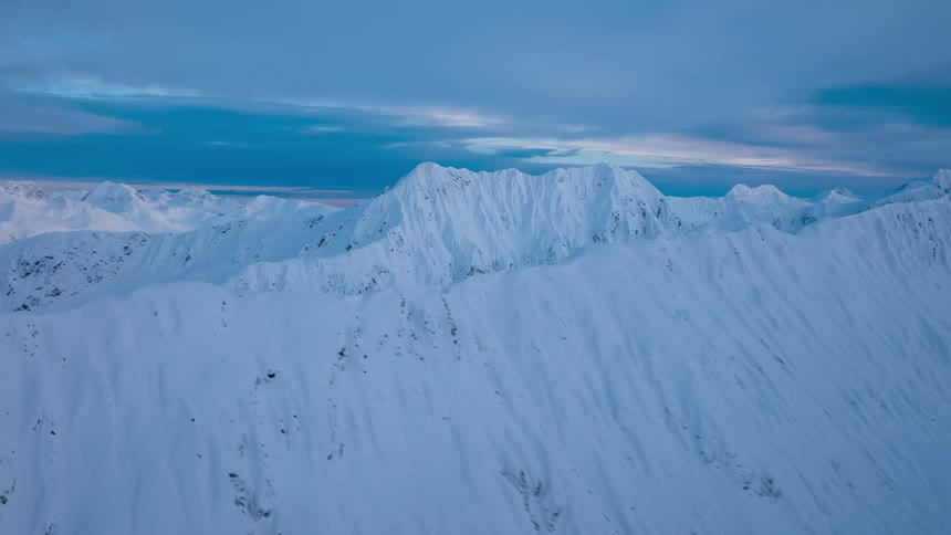 A vast mountain range covered in thick snow during the day
