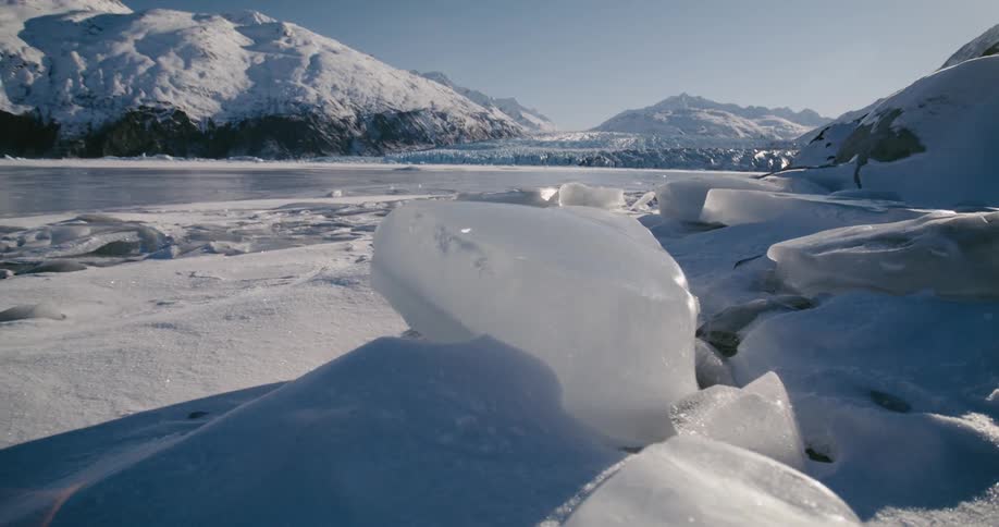 A frozen lake surrounded by snowy mountains and ice