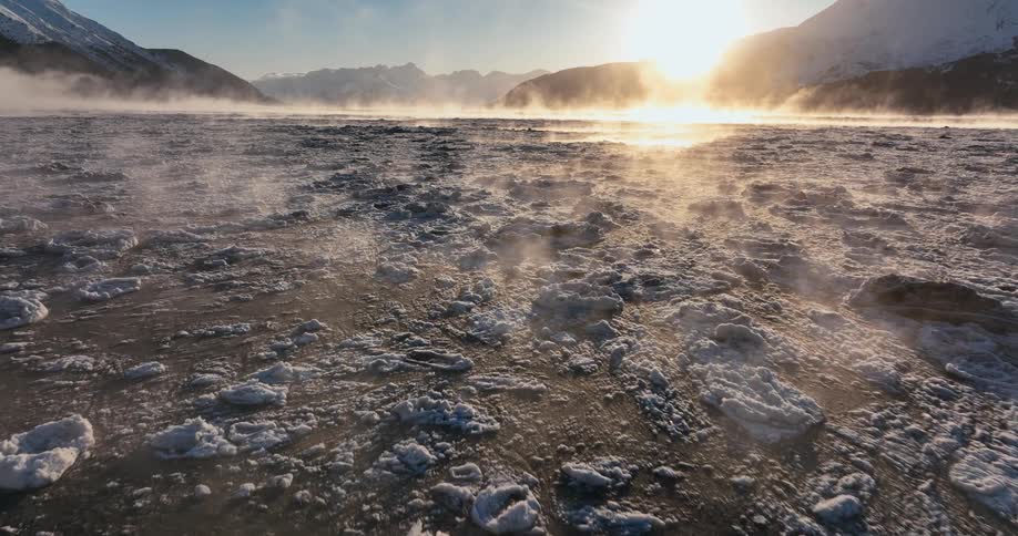 Steam rises from the ice on the water
