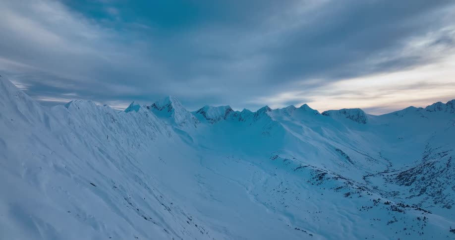 A snow covered mountain ridge under a cloudy daytime sky