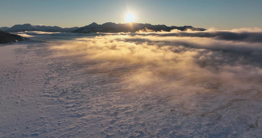 An aerial view of clouds over a snow covered field