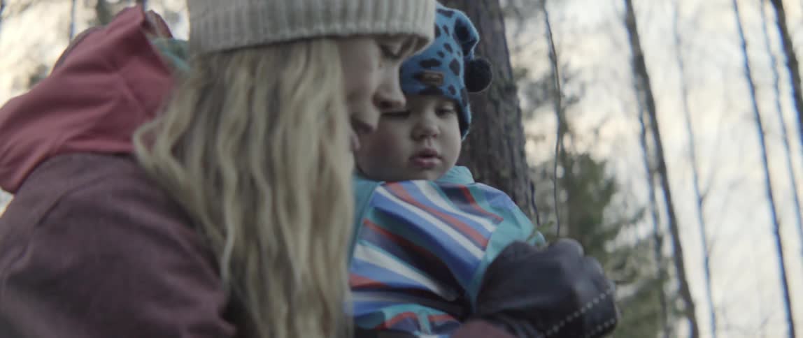 A woman picks up some vegetation and explains it to her toddler