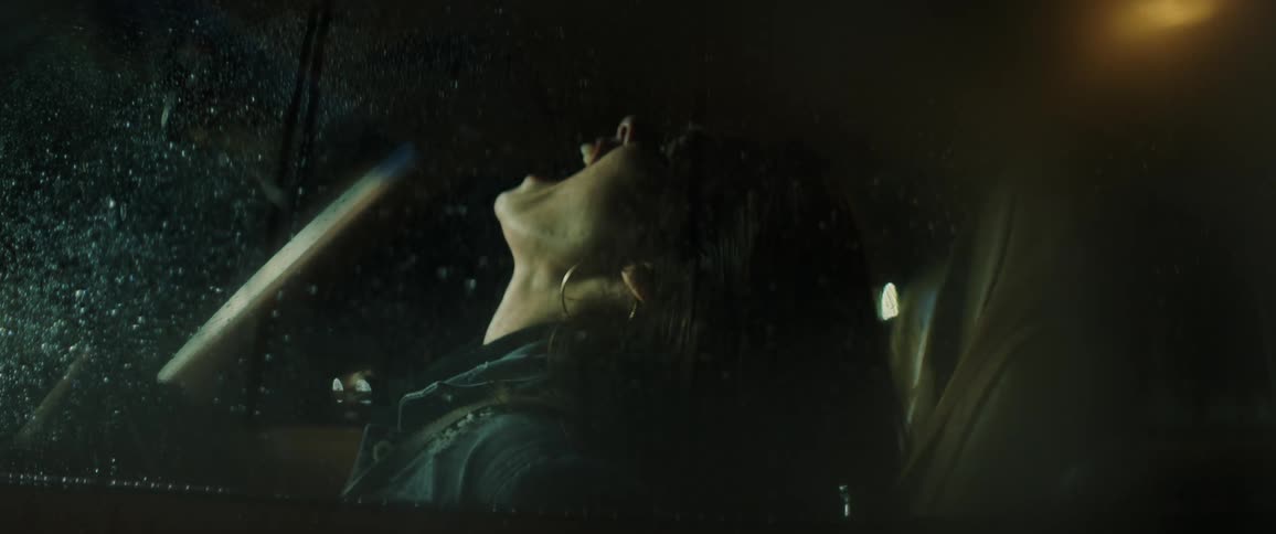 Woman with hoop earrings and jacket has a breakdown in car at night