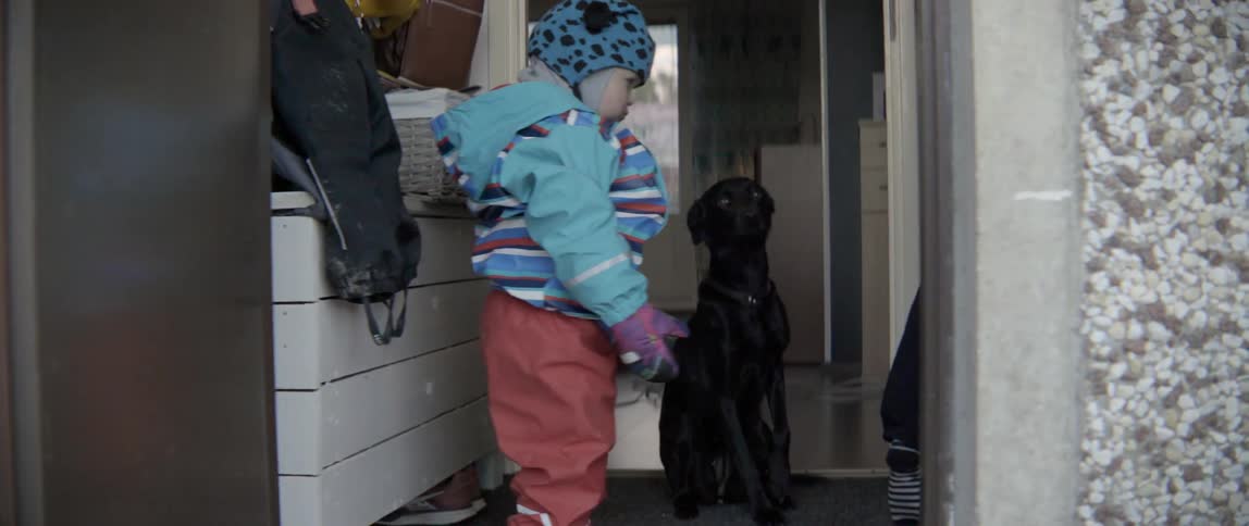 A child bundled up for the cold waits while his mom deals with the dog