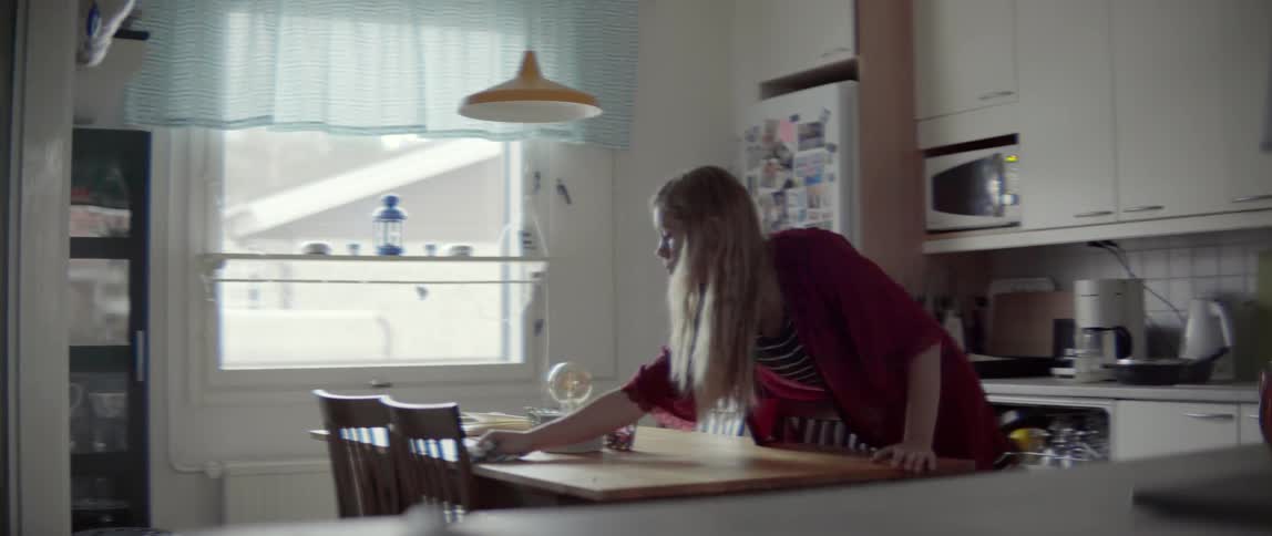A woman cleans up a table in an apartment during the day