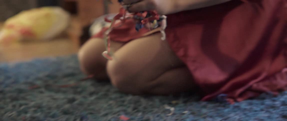 Young woman picking up scraps of paper and litter from the floor at home.