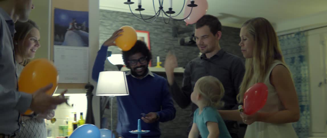 Joyful family and friends celebrating a special occasion with colorful balloons in a home.