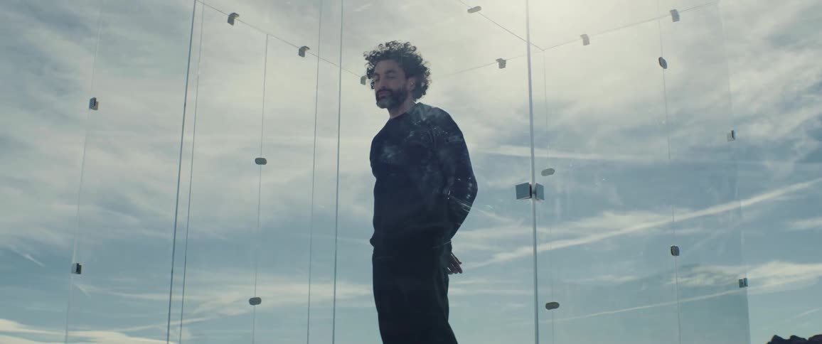 A man is inside a glass window box in the middle of nowhere