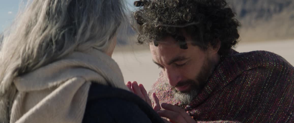 A man is touching a woman in the desert
