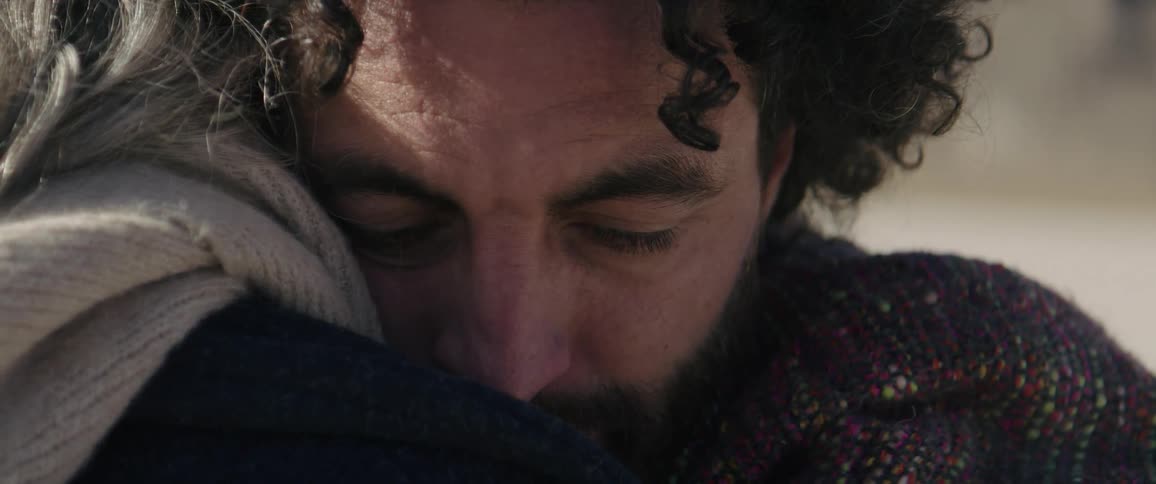 A man closes his eyes as he hugs a woman tightly