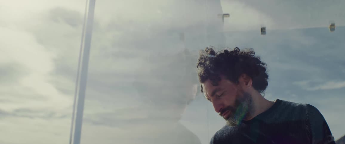 A man leans against the glass wall