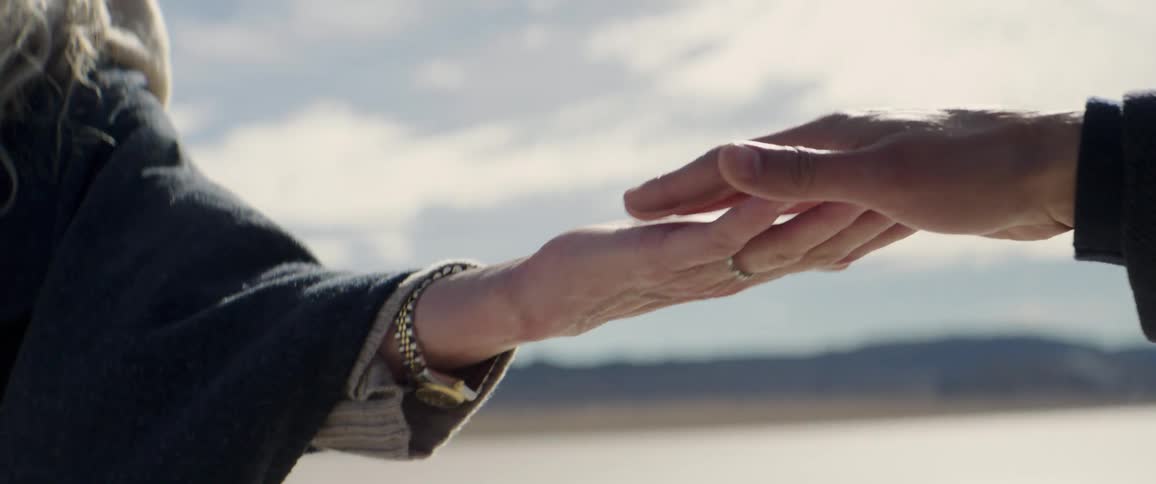 Close of of a man and womans hands as they reach towards one another and run their fingers along each others