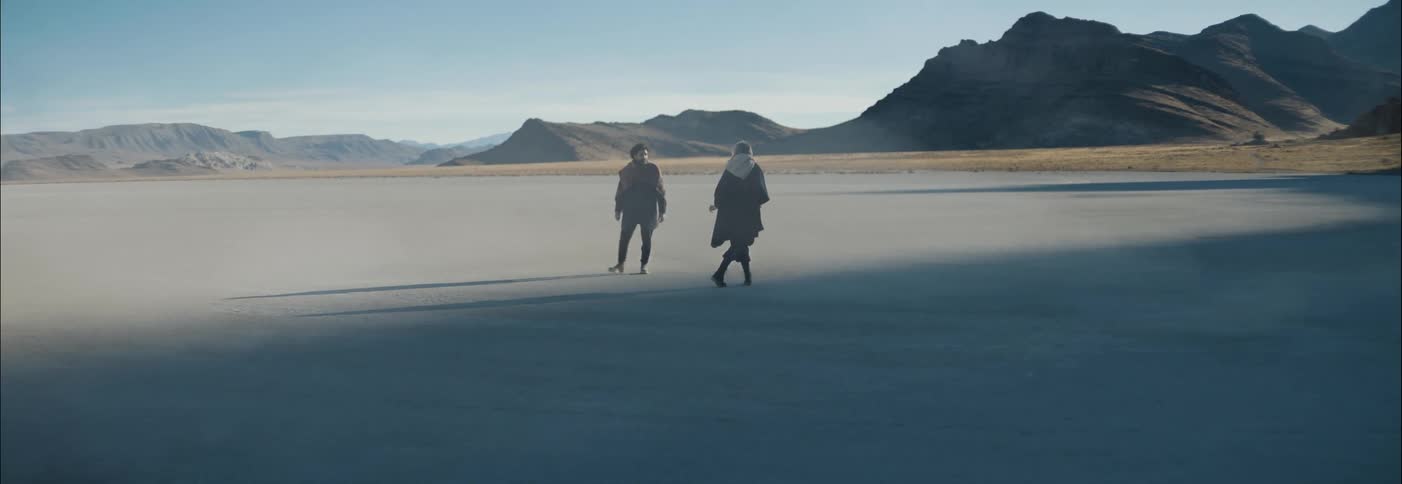 A man and woman circle around each other in the desert