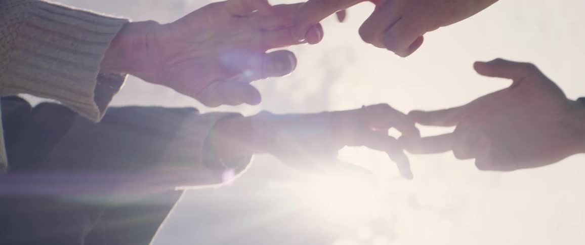 Two people holding hands slowly move apart and separate their hands while standing on sunny day