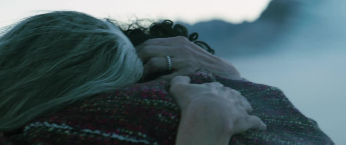 Elderly woman and man hug closely standing outdoors in smokey area