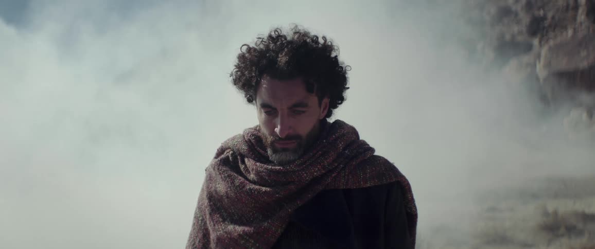 A man stands still as strong winds dirt in his face in the desert