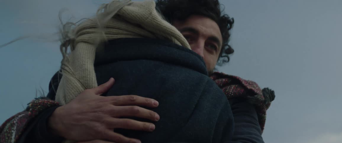 Man and woman stand outdoors hugging each other