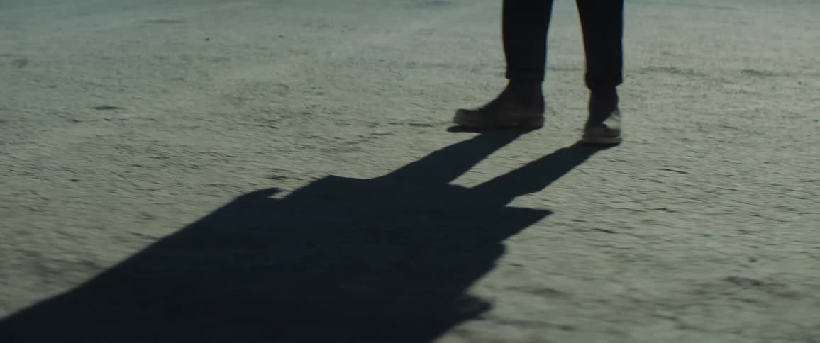 Close up of a persons feet as they walk sideways in a desert area