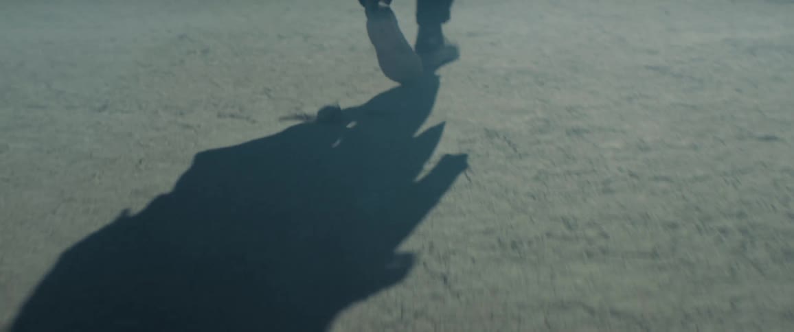 A man shuffles his way across very dry cracked earth