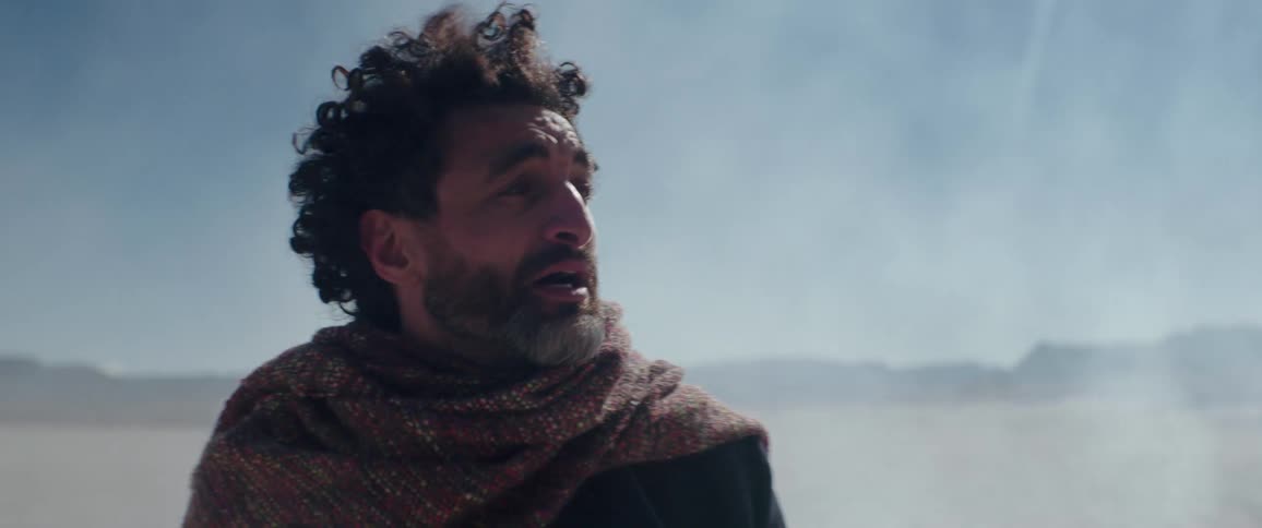 A man looks around and yells in the desert
