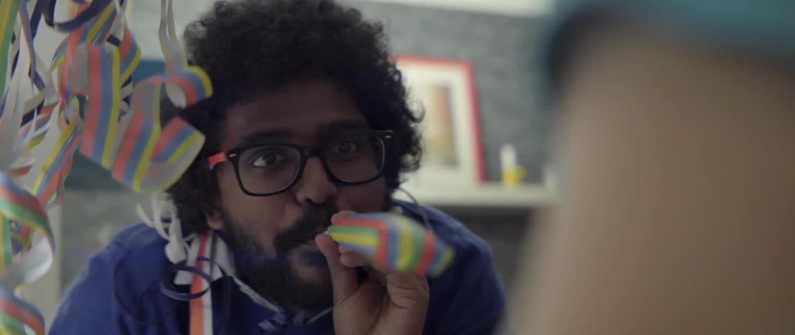 Young man blowing a festive party horn during a joyful New Year's Eve party.