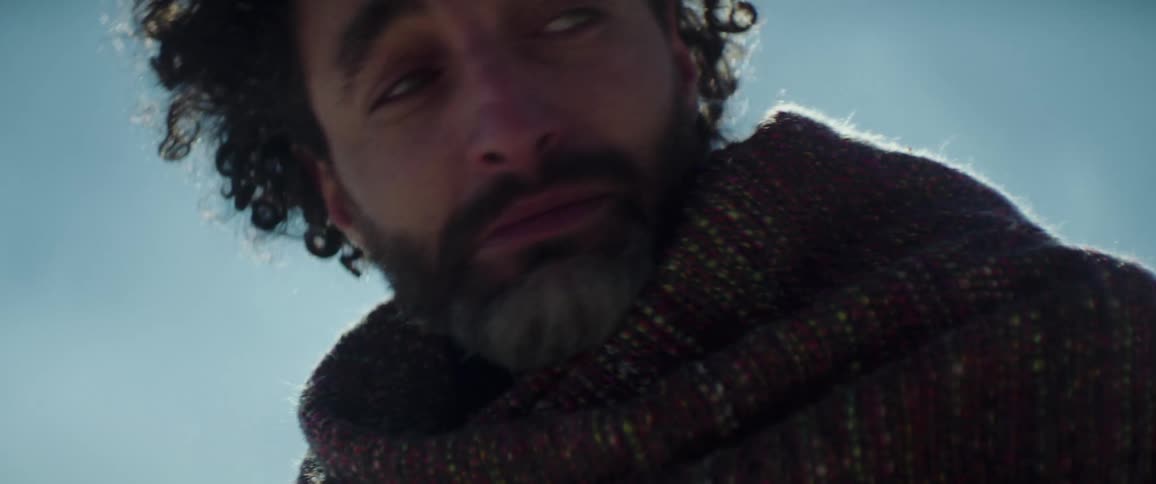 A man looks around and cries as he stands near cliffs