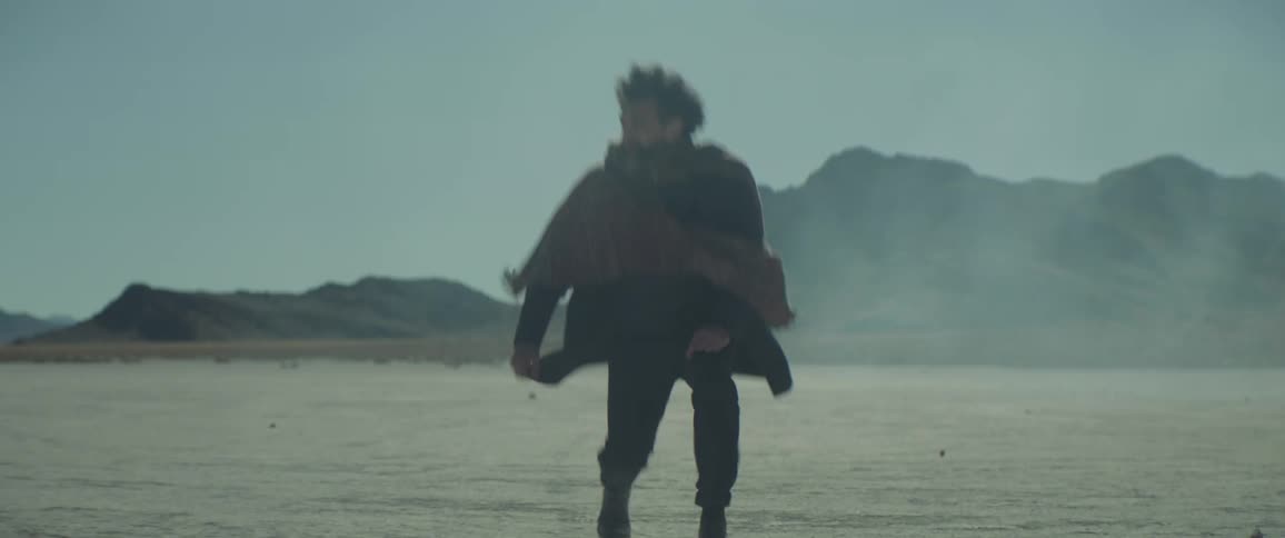 A man walking across a desert drops to his knees